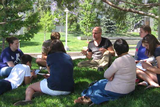 people gathered around spiritual leader on grass